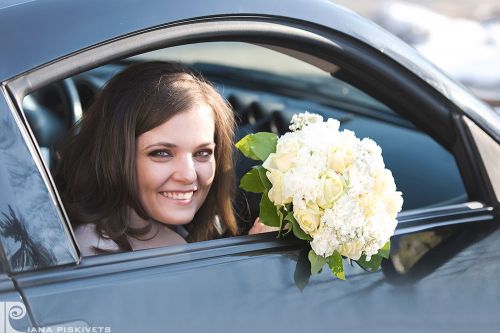 Newlyweds in a car, a beautiful woman with flowers, wedding car, bride's bouquet, a photo shoot in Warsaw, a white wedding dress of marriage, photo shoot. Professional wedding photographer Poland registrar in Pruszkow bride with a bouquet.